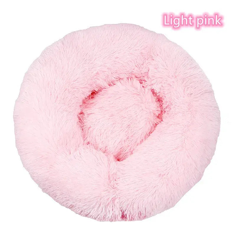 Light pink plush round pet bed for small dogs and cats, offering comfort and anxiety relief.