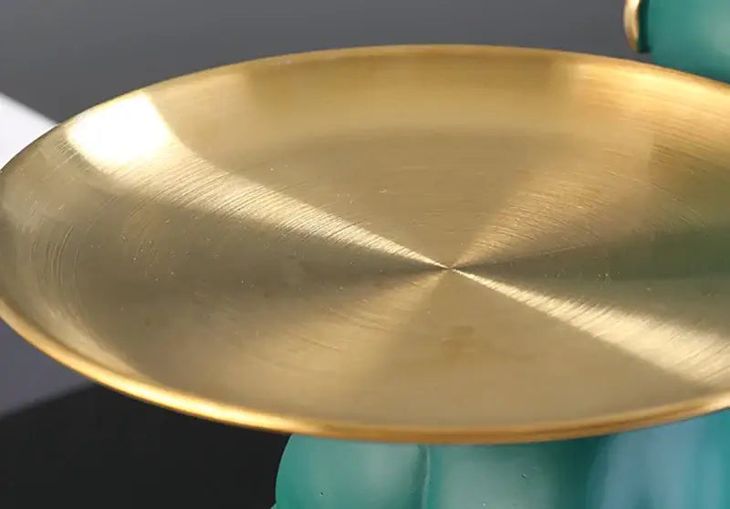 Close-up of a shiny brass plate atop a turquoise resin base, designed for decorative storage.
