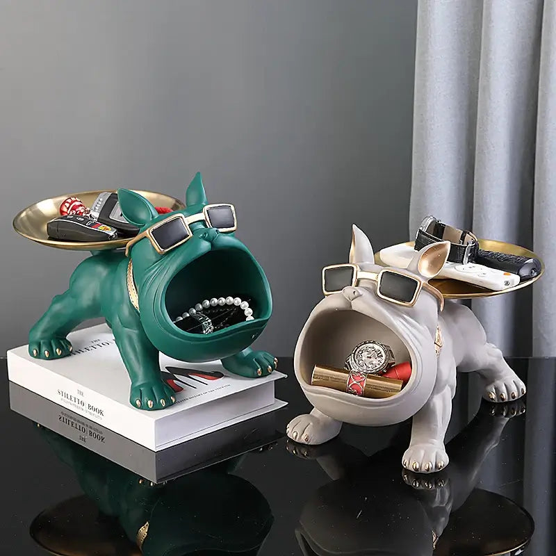 Two Bulldog resin statues in green and white, wearing sunglasses and holding jewelry on a table for home decor and storage.