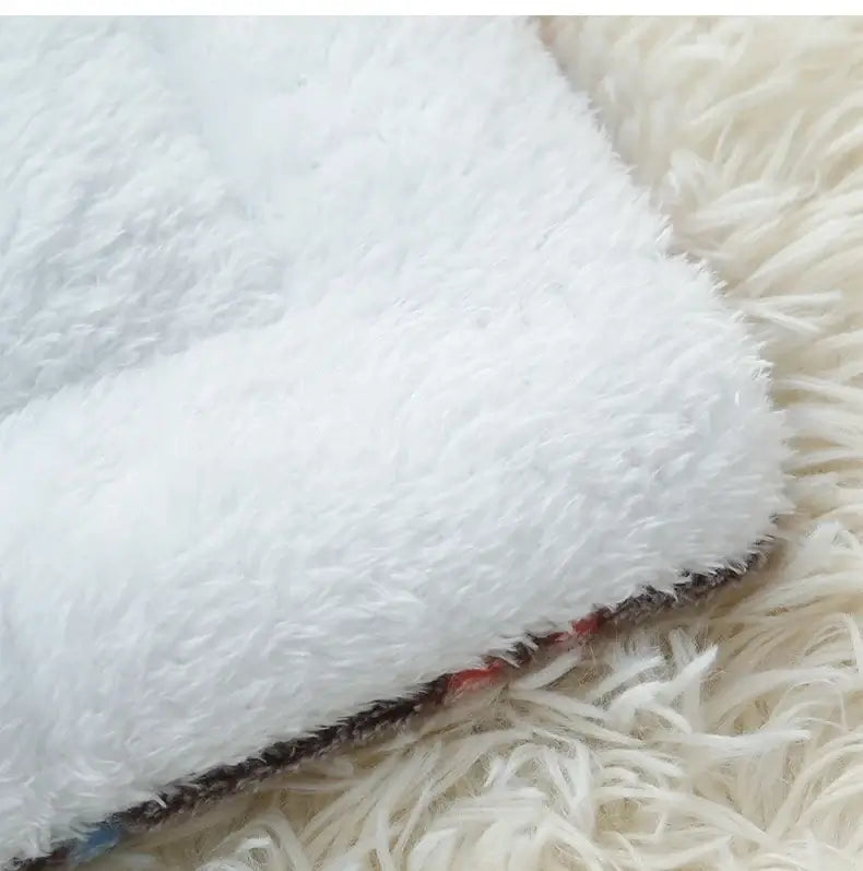 Close-up of the soft coral velvet fabric of the Paw-some Flannel Pet Sleeping Mat on a fluffy background.