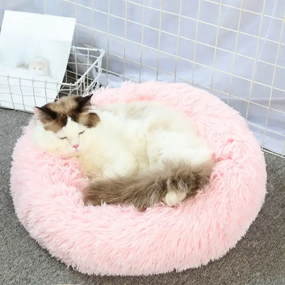 Fluffy pink round pet bed with a sleeping cat, perfect for small dogs and cats, offering comfort and anxiety relief.