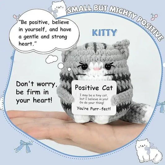 Handmade crochet cat ornament doll with motivational quotes in a person's hand, showcasing positive energy and charm.
