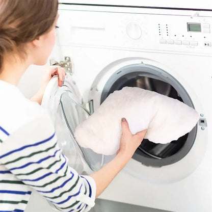 Woman loading a plush pet bed into a washing machine for easy cleaning and maintenance.